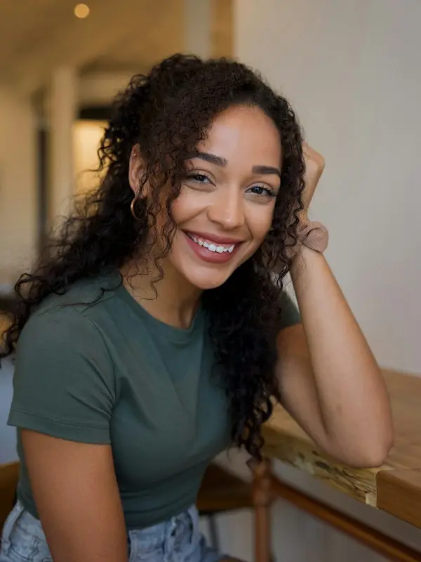 Woman with curly hair smiling at a café table